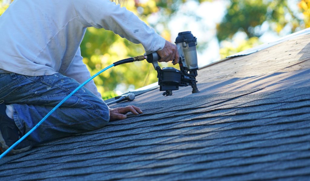 Roofing contractor installing a standard roof with a nailgun